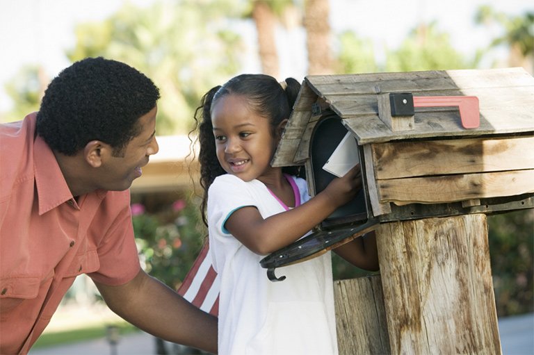 Father with daughter grabbing mail out of mailbox